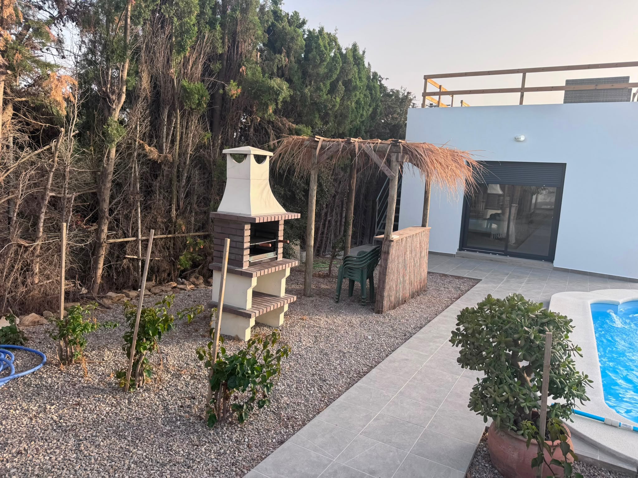 Zona de barbacoa y palapa junto a la piscina