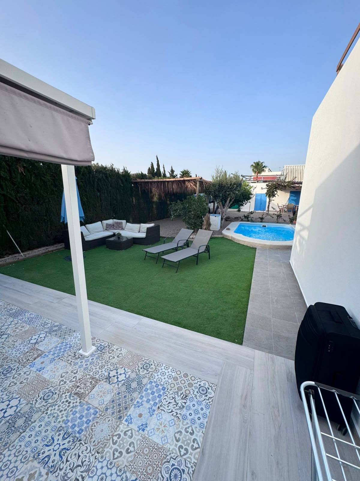 Terraza con suelo hidráulico, tumbonas y piscina al fondo