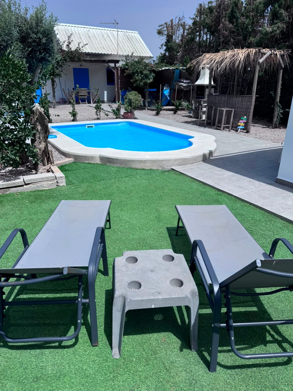 Tumbonas frente a la piscina con jardín y palapa