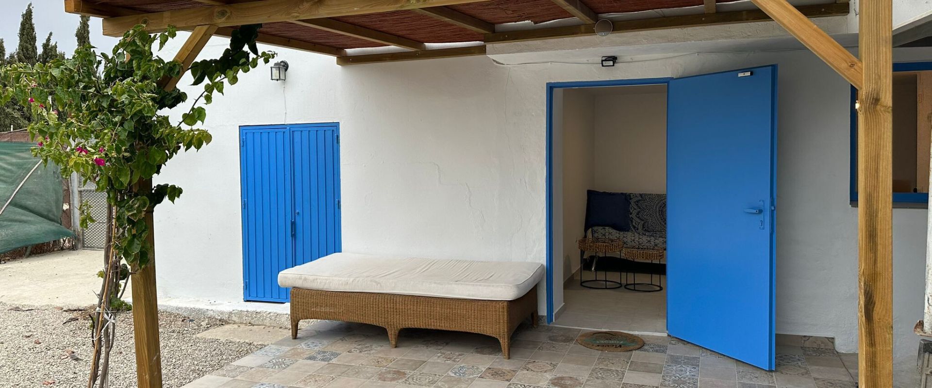 Porche pequeño techado en la entrada de la Vivienda con pequeña mesa de Jardín para 2/3 personas